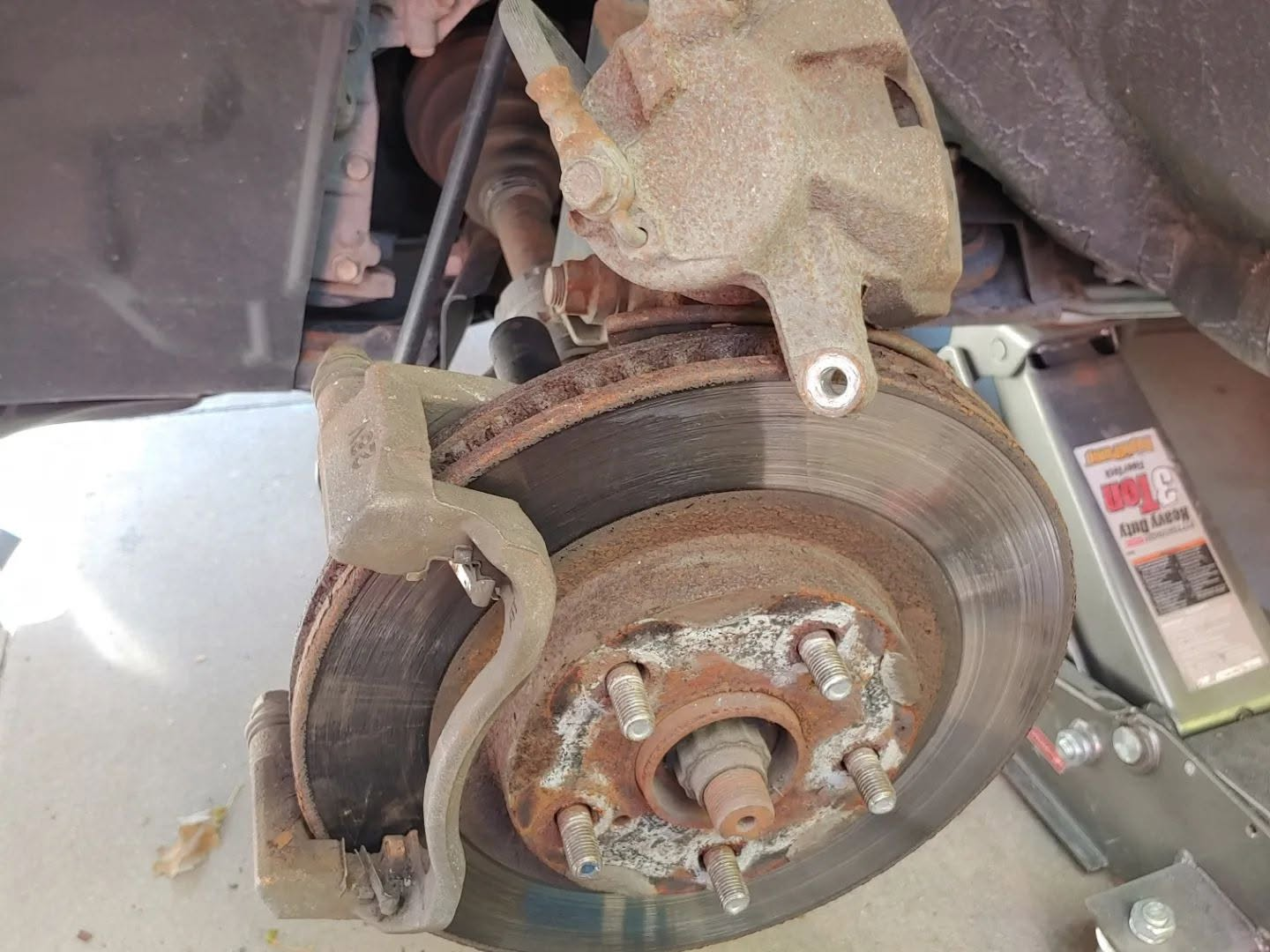 Old corroded brake rotor with caliper bracket visible